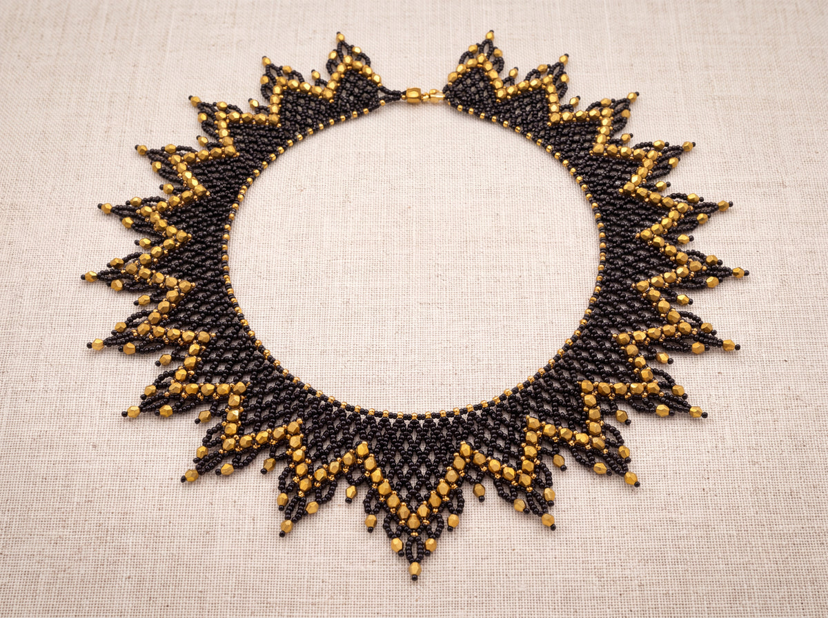 Black and gold sunburst collar laid flat from above on oatmeal linen