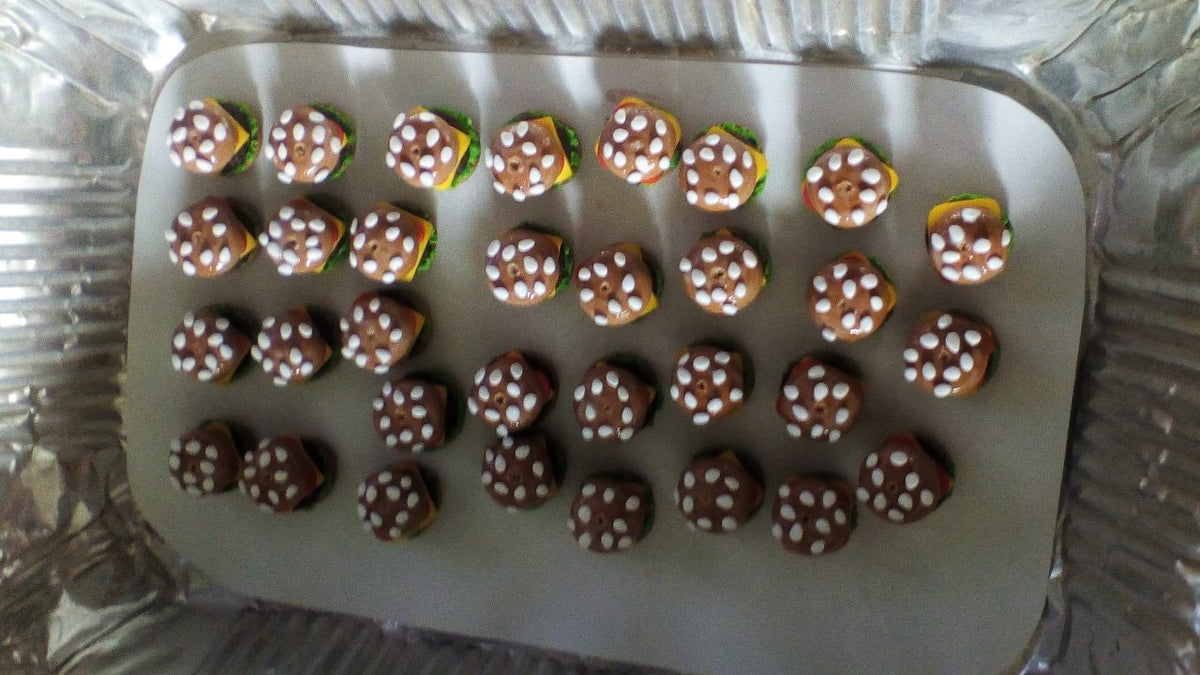 Sesame-topped polymer clay burger bun charms lined up in a tray, work in progress for Hamburger earrings