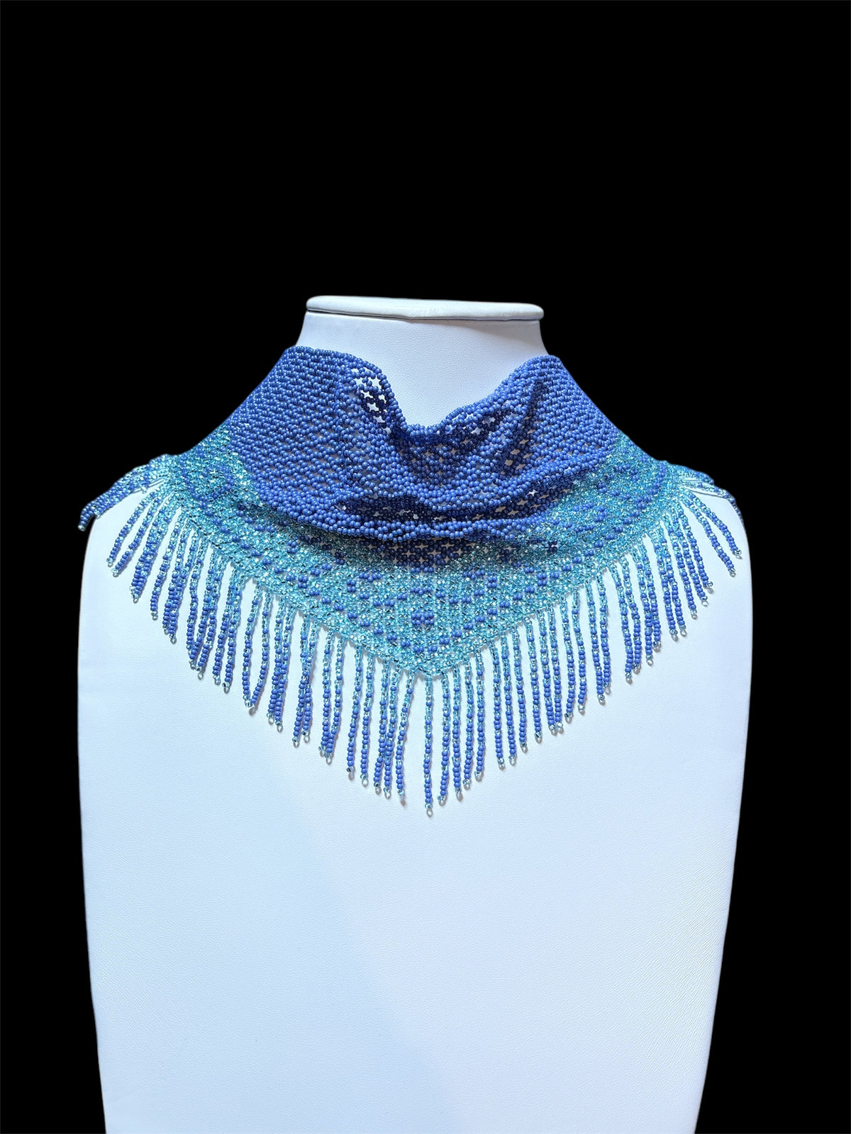 Periwinkle blue and aqua beaded scarf necklace with fringe, displayed on a white bust against black