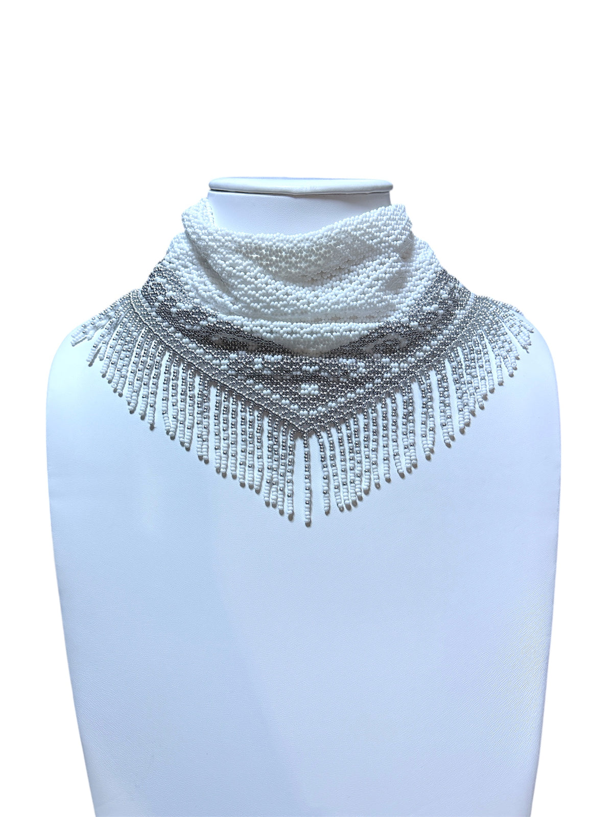 White and silver handmade beaded scarf necklace with patterned border and fringe on a white display bust