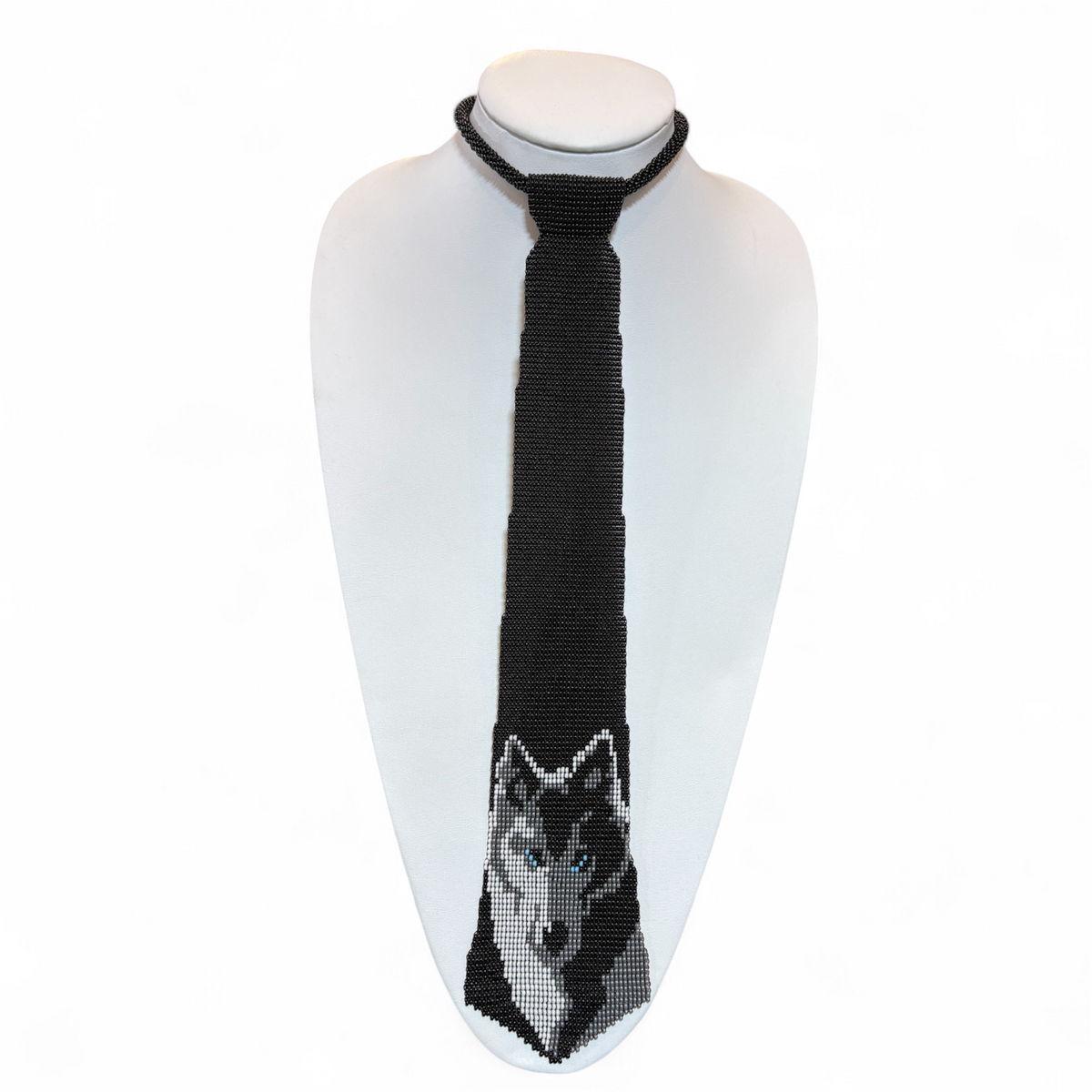 Handmade beaded tie with a gray wolf portrait woven in black seed beads, displayed on a white bust
