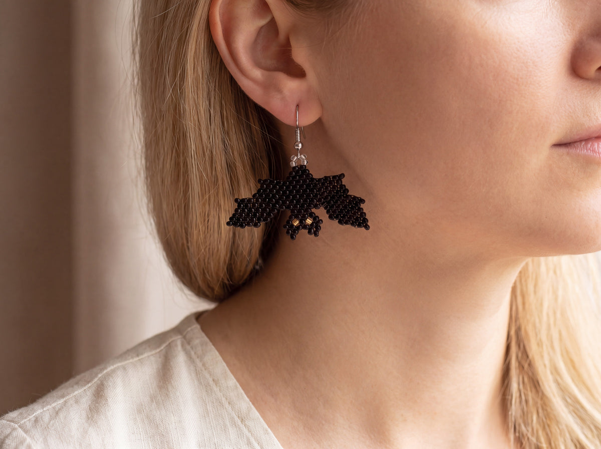 Black beaded bat earring with gold eyes worn on the ear, showing true size