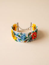 Handmade loomed beaded cuff bracelet with sunflower and poppy motifs on a white background, glass seed beads