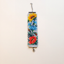Handmade loomed bracelet of glass seed beads with sunflower, cornflower and red poppy folk motif on white