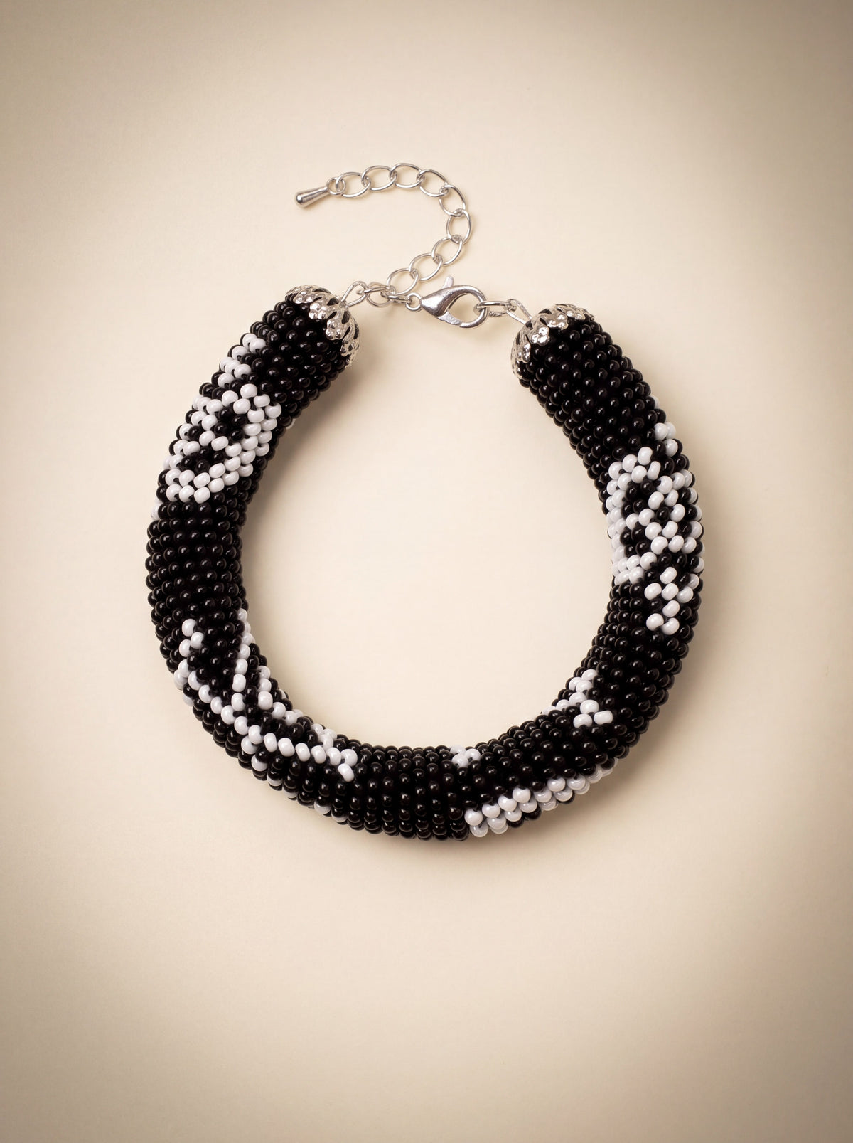 Handmade bead crochet bracelet in black and white geometric skull pattern with silver clasp