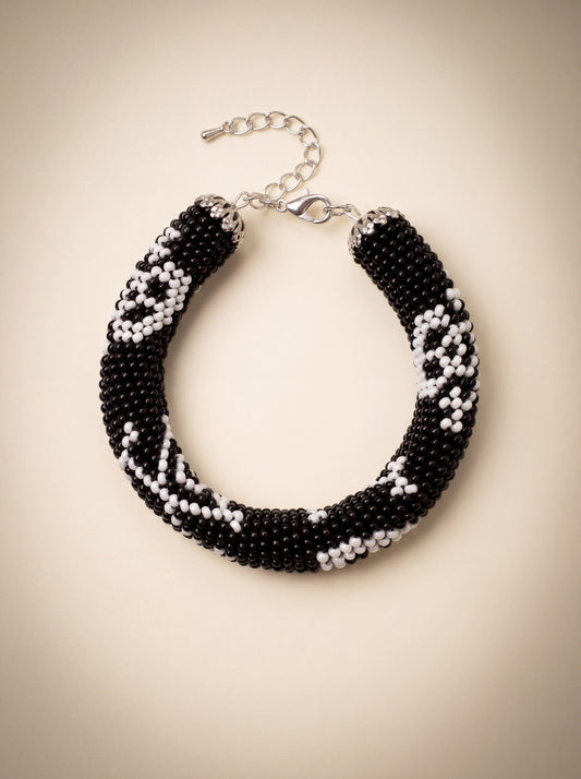 Handmade bead crochet bracelet in black and white geometric skull pattern with silver clasp