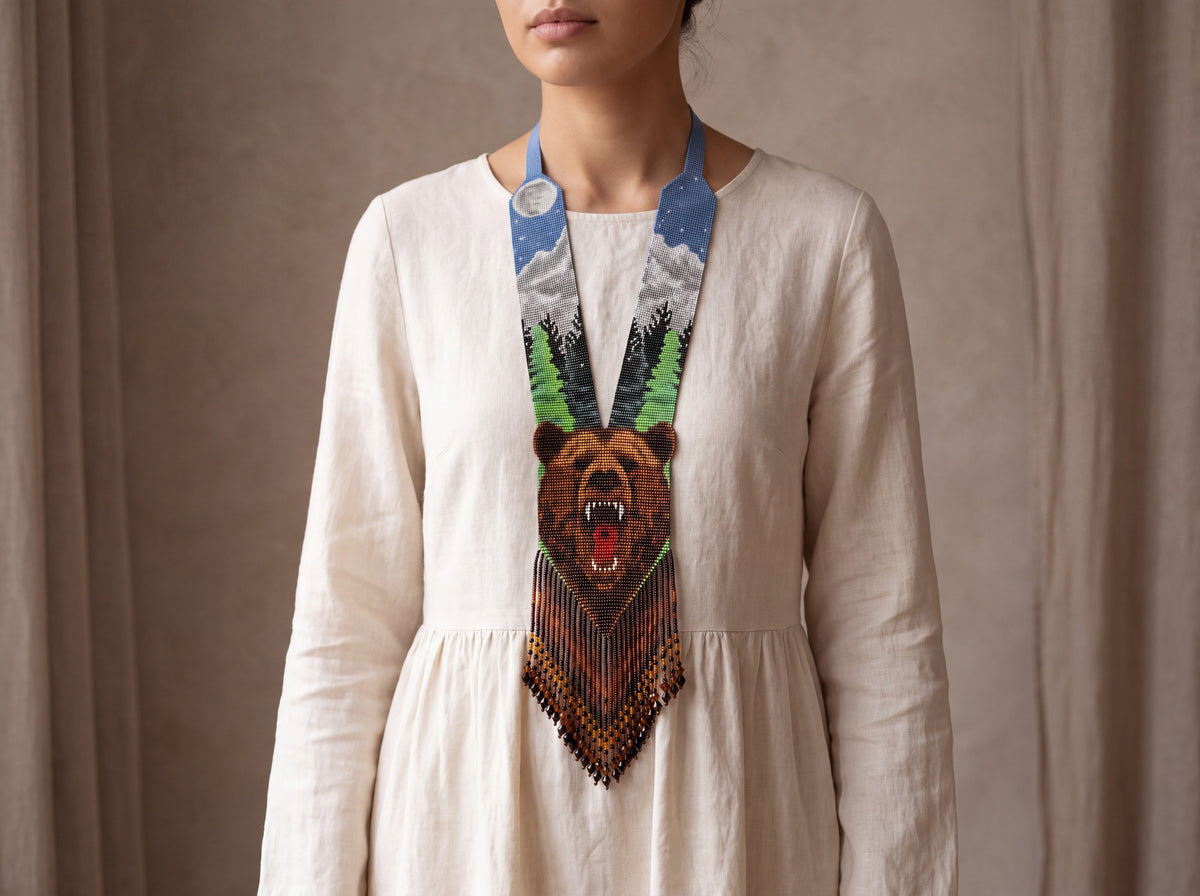 Handwoven beaded gerdan necklace with a roaring bear, moonlit forest scene and amber fringe, worn over a cream linen dress.