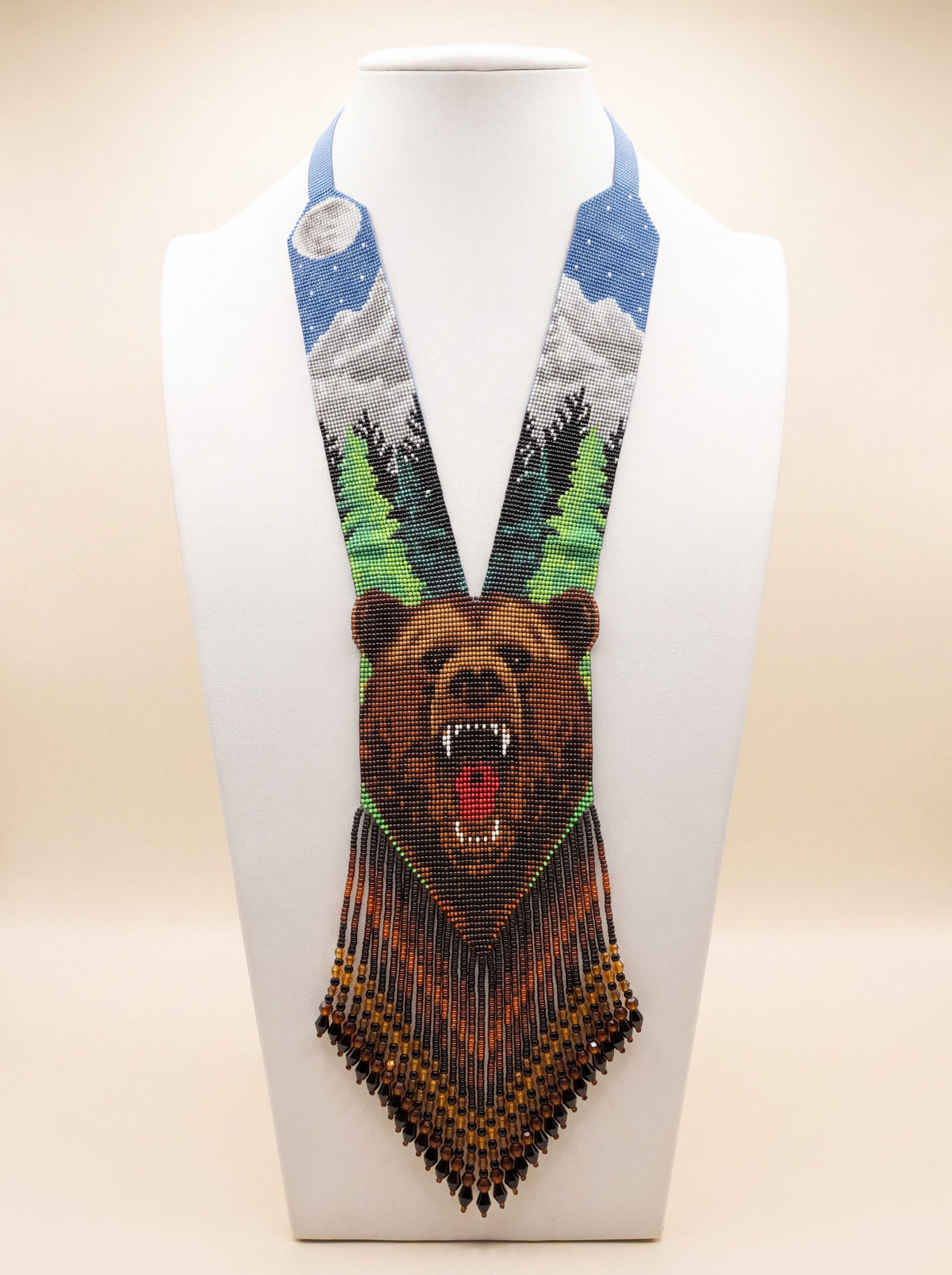 Handmade beaded gerdan necklace with a growling bear face motif, snowy mountain and pine forest scene in blue, green and brown