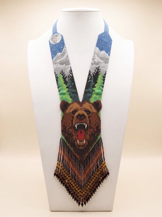 Handmade beaded gerdan necklace with a growling bear face motif, snowy mountain and pine forest scene in blue, green and brown