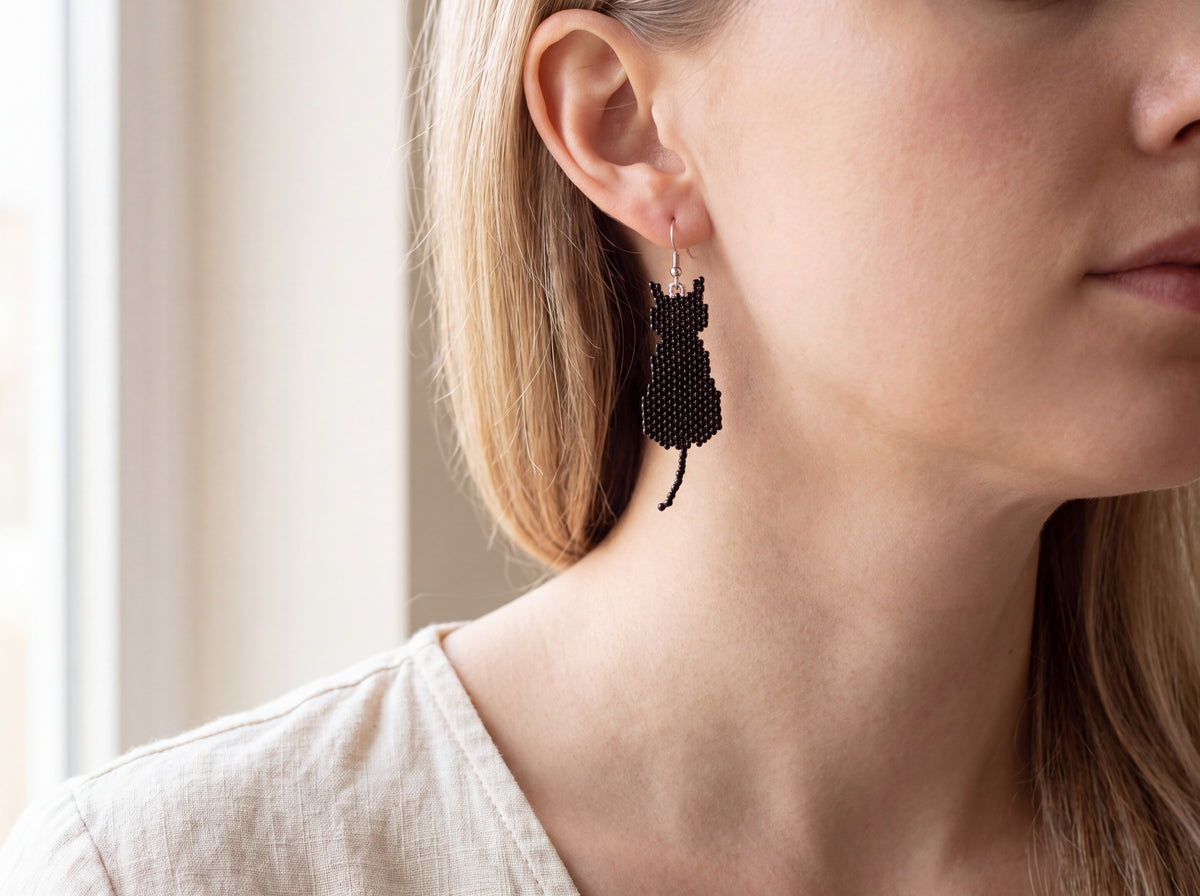 Black beaded cat silhouette earring worn on the ear, showing true size