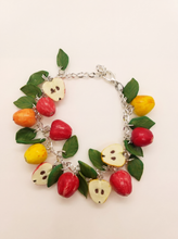 Handmade polymer clay charm bracelet with red and yellow apples, apple halves and green leaves on silver chain