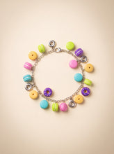 Handmade polymer clay charm bracelet with colorful donut and macaron charms on a silver chain.