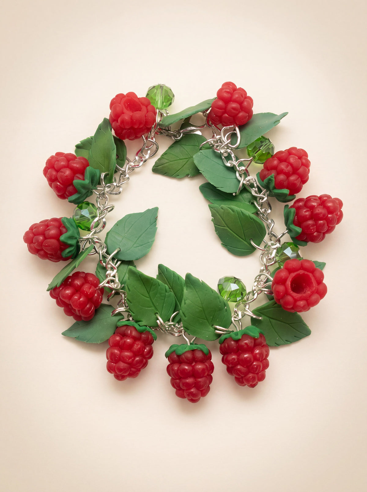 Handmade polymer clay raspberry charm bracelet with red berries and green leaves on a silver chain
