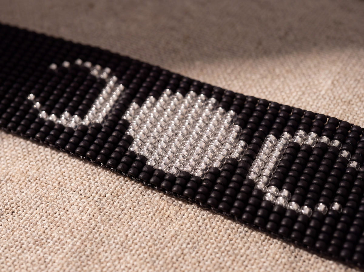 Macro detail of the silver beaded full moon and crescents on the matte black loomed band