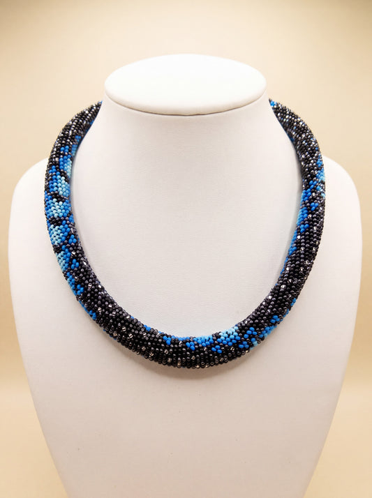 Handmade bead crochet rope necklace with a black, blue, and turquoise snake-print pattern.