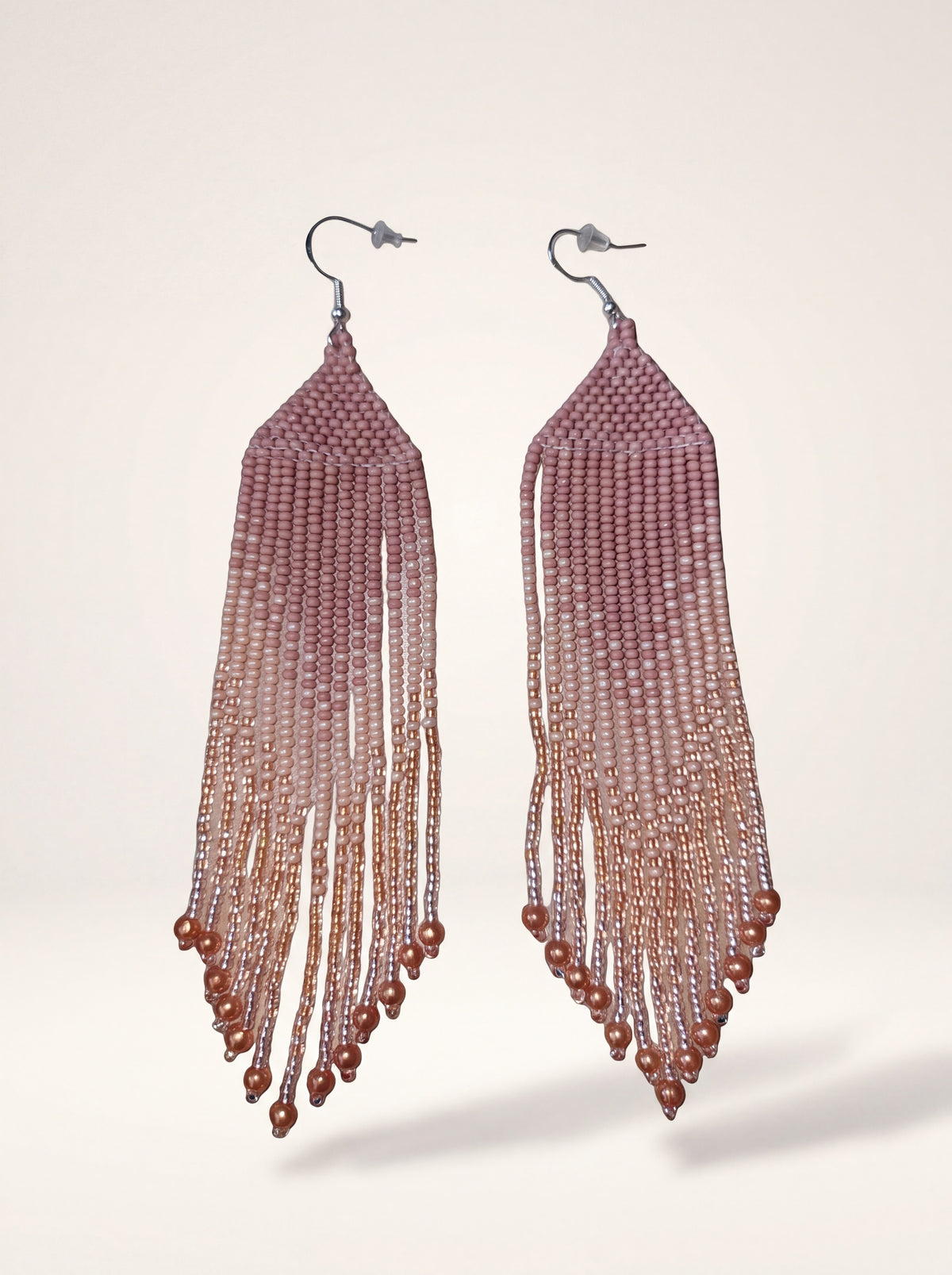 Handmade fringe earrings in dusty pink ombre glass seed beads with copper accents on cream backdrop