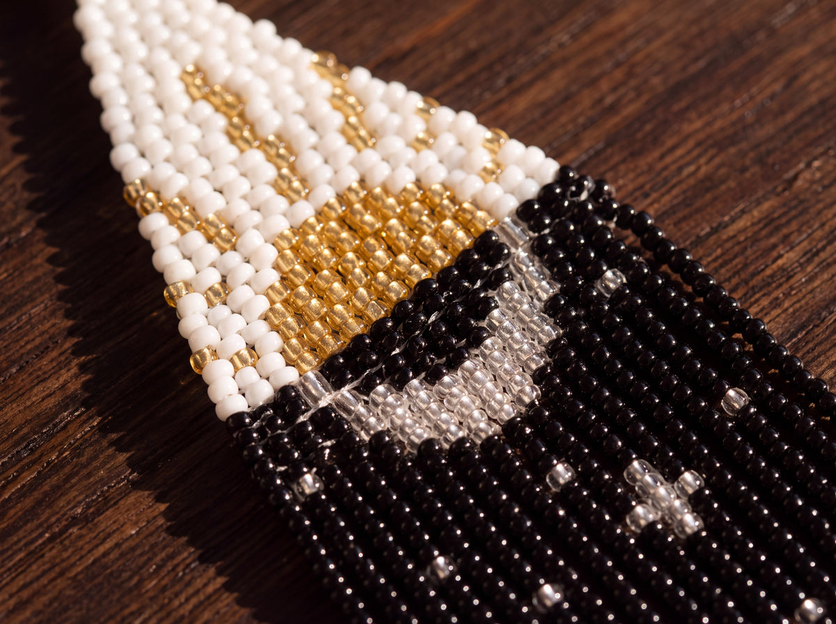 Macro detail of the gold beaded sun, silver crescent moon and black night beadwork, on dark wood