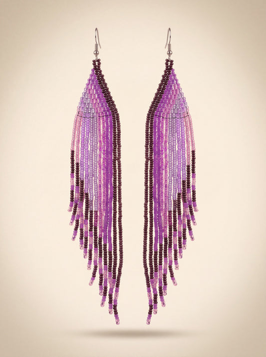 Extra long handmade beaded fringe earrings in purple, lilac and dark plum seed beads hanging side by side, on cream