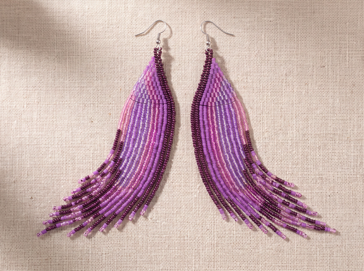 Pair of extra long purple beaded fringe earrings fanned side by side on oatmeal linen