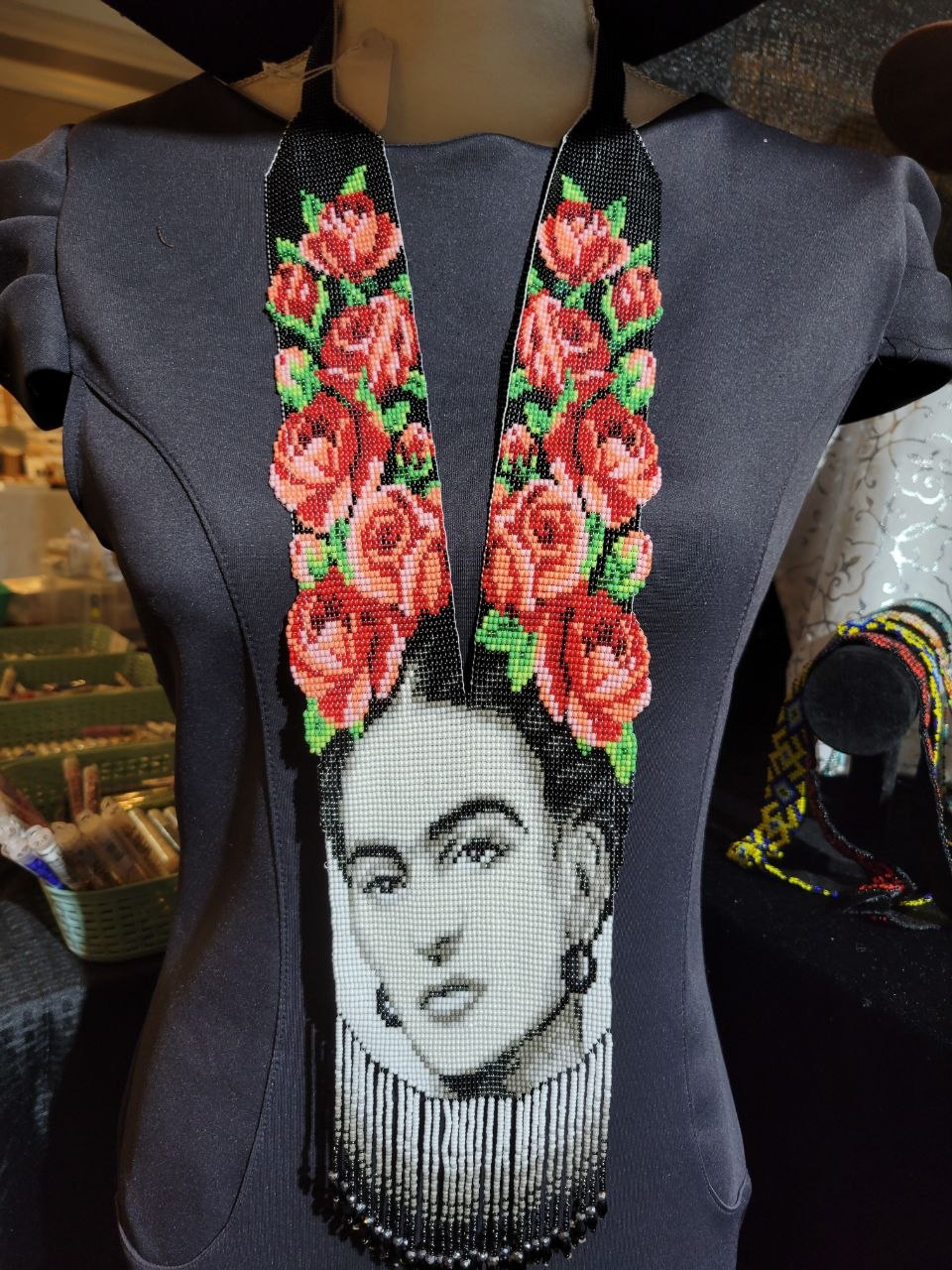 Frida beaded portrait necklace worn on a mannequin in a dark dress