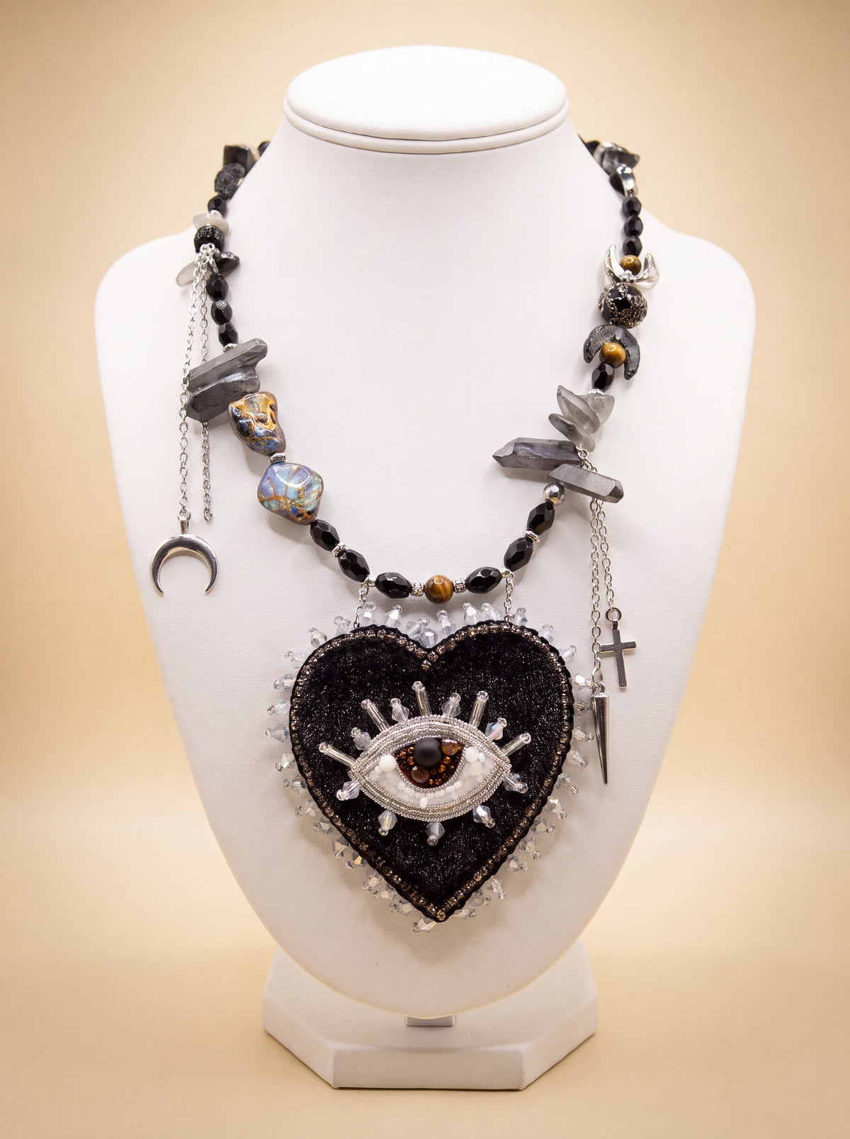 Handmade black beaded heart necklace with embroidered eye, crystal edging, charms and crystal points, on a white bust