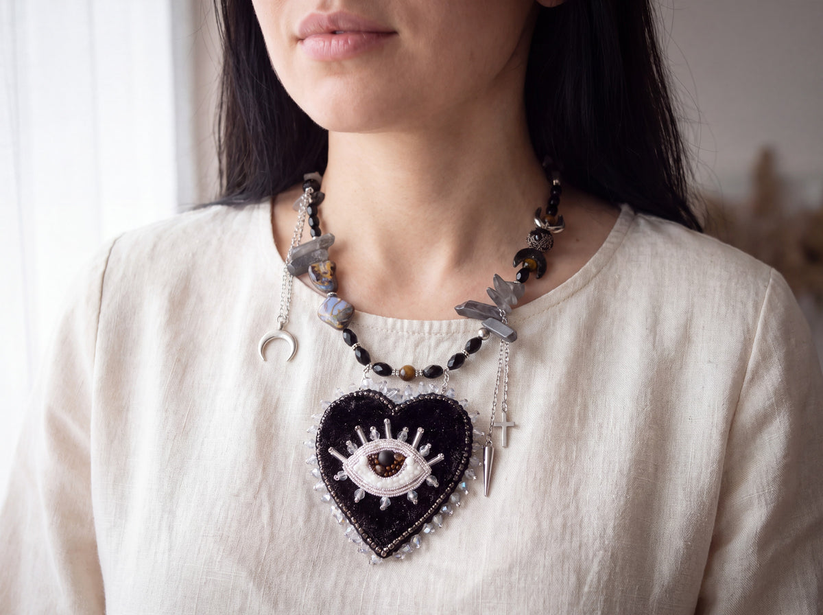 Black heart evil eye necklace worn, heart pendant resting on the chest