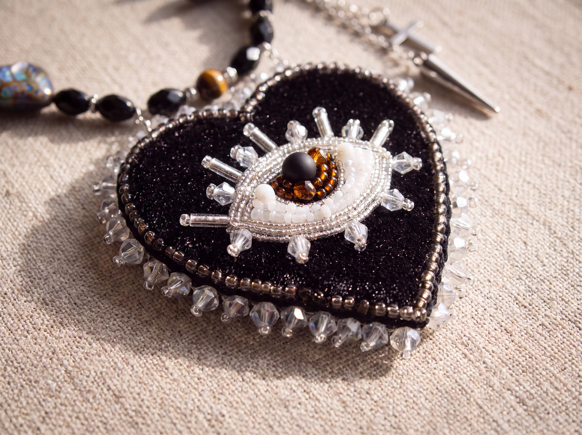 Macro detail of the bead-embroidered eye in the black beaded heart with crystal edging
