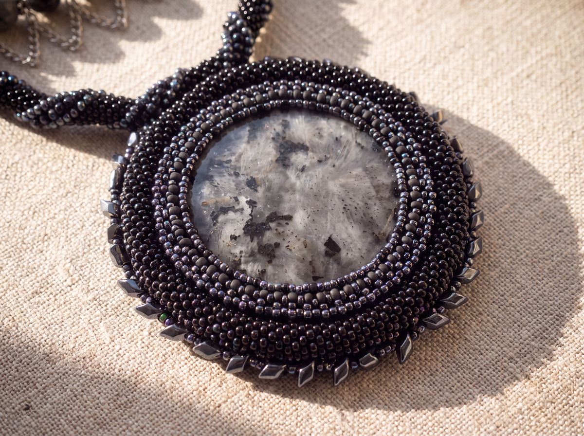 Macro detail of the larvikite stone medallion in its black beaded bezel with crystal edging