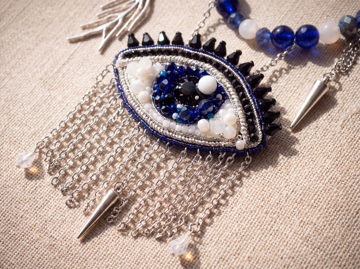 Macro detail of the bead-embroidered eye pendant with black crystal lashes and chain fringe