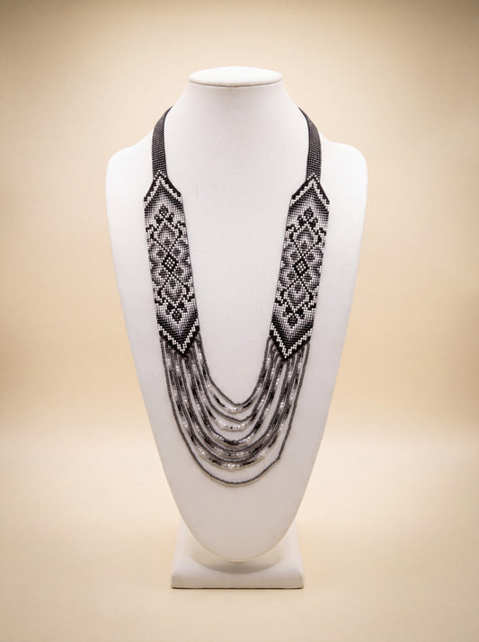 Handmade beaded necklace "Nadiia" with loomed black and white diamond pattern medallions and beaded fringe.