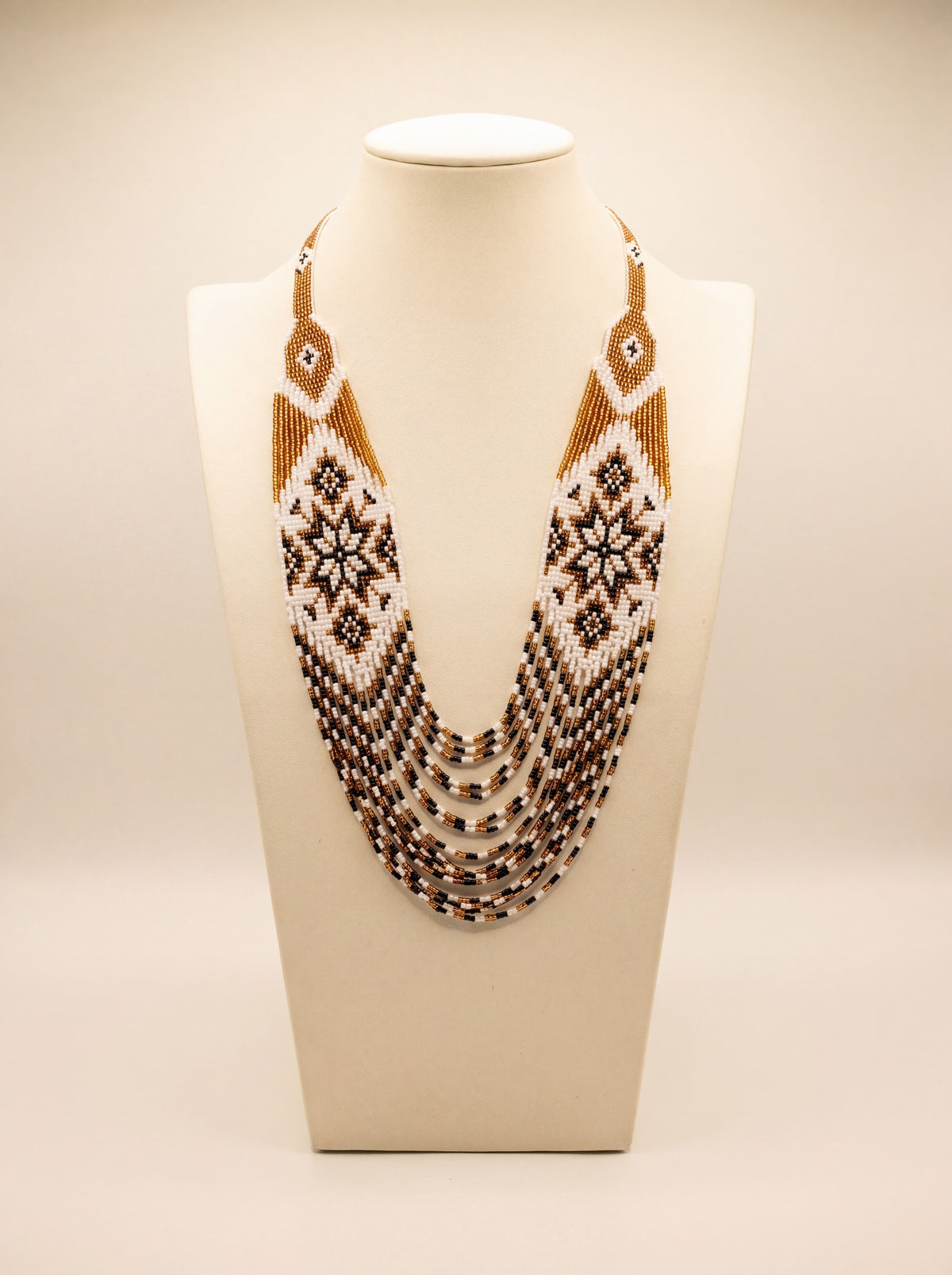 Handmade beaded necklace "Odarka Gospodarka" with loomed gold, white and black star motif panels and fringe strands.