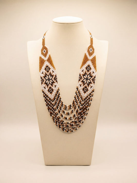 Handmade beaded necklace "Odarka Gospodarka" with loomed gold, white and black star motif panels and fringe strands.