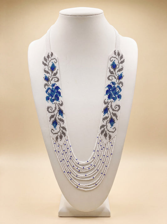 Handmade beaded necklace "Prolisok" with loomed blue floral pattern on white and beaded fringe strands.