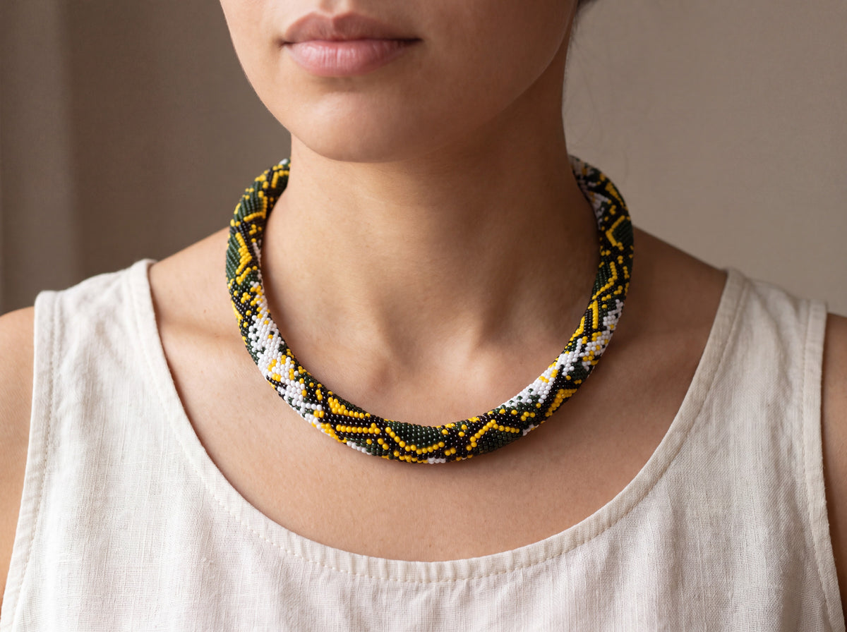 Handmade bead-crochet rope necklace with python snakeskin pattern in green, yellow, black and white, worn as a choker on a model