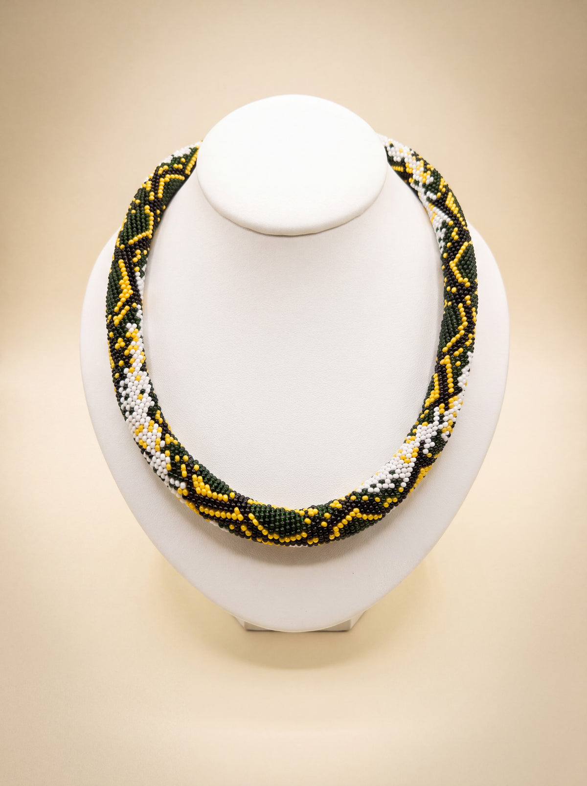 Handmade bead-crochet rope necklace with a green, yellow and white snake-scale pattern.