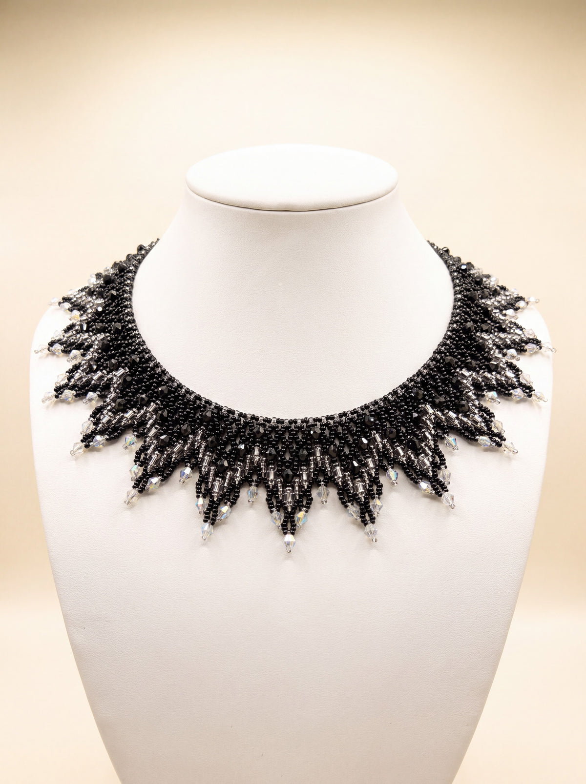 Handmade beaded sunburst collar in black and silver-grey with clear crystal-tipped points, on a white bust