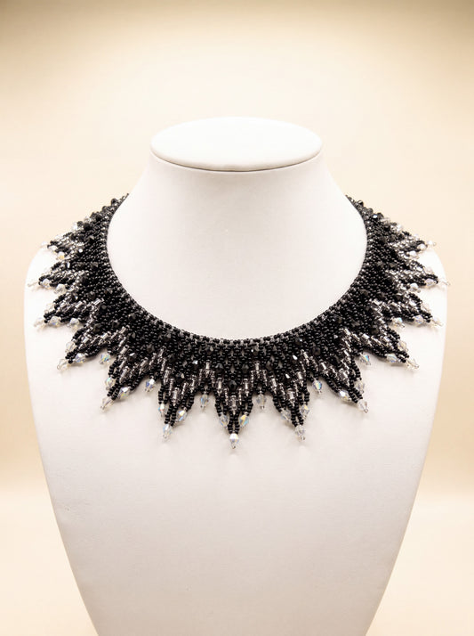 Handmade beaded sunburst collar in black and silver-grey with clear crystal-tipped points, on a white bust