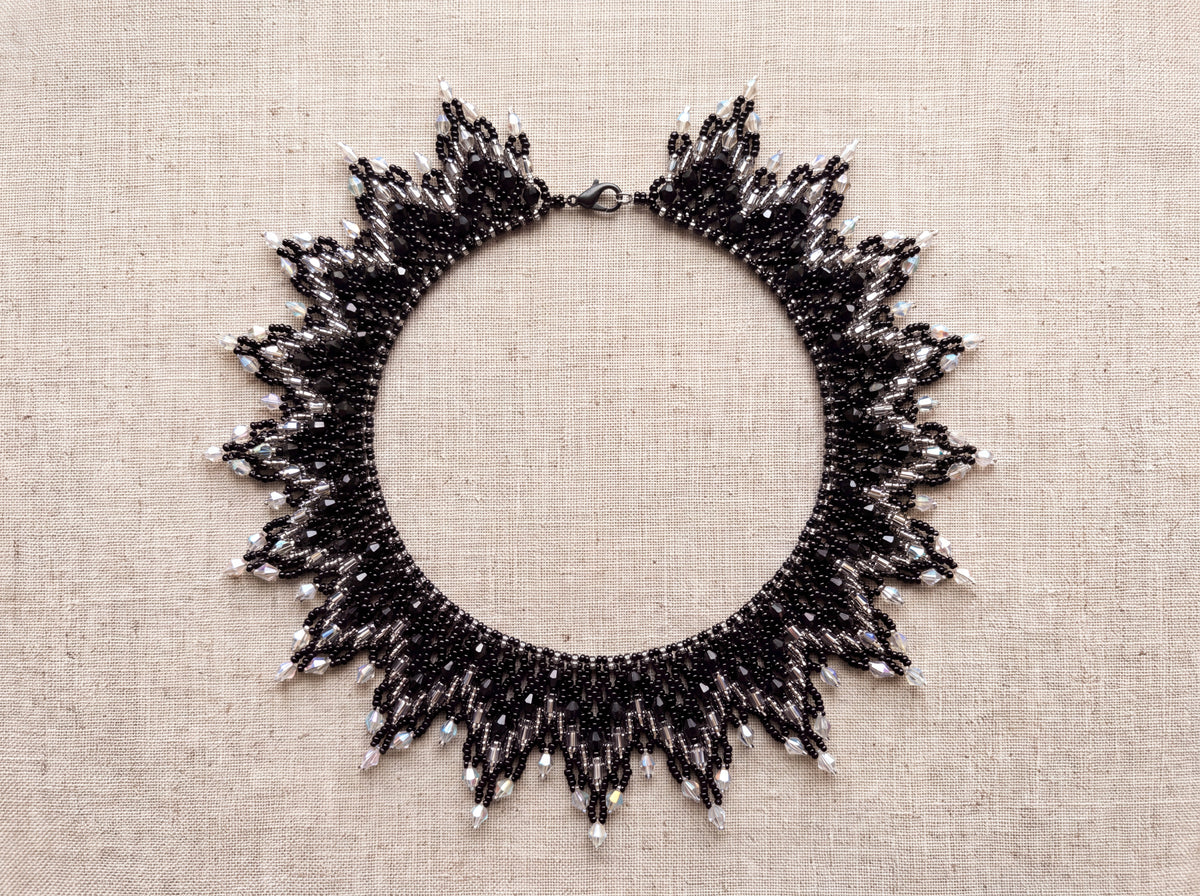 Grey sunburst collar laid flat from above on oatmeal linen
