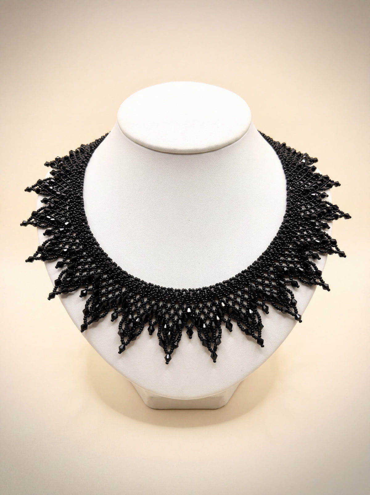 Handmade all-black beaded sunburst collar with crystal-tipped points, on a white bust