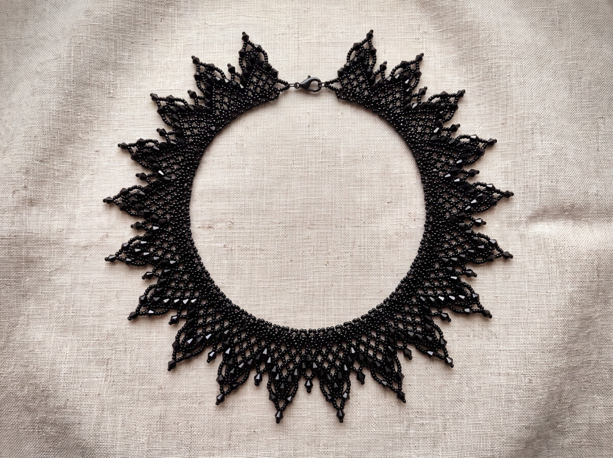 Black sunburst collar laid flat from above on oatmeal linen