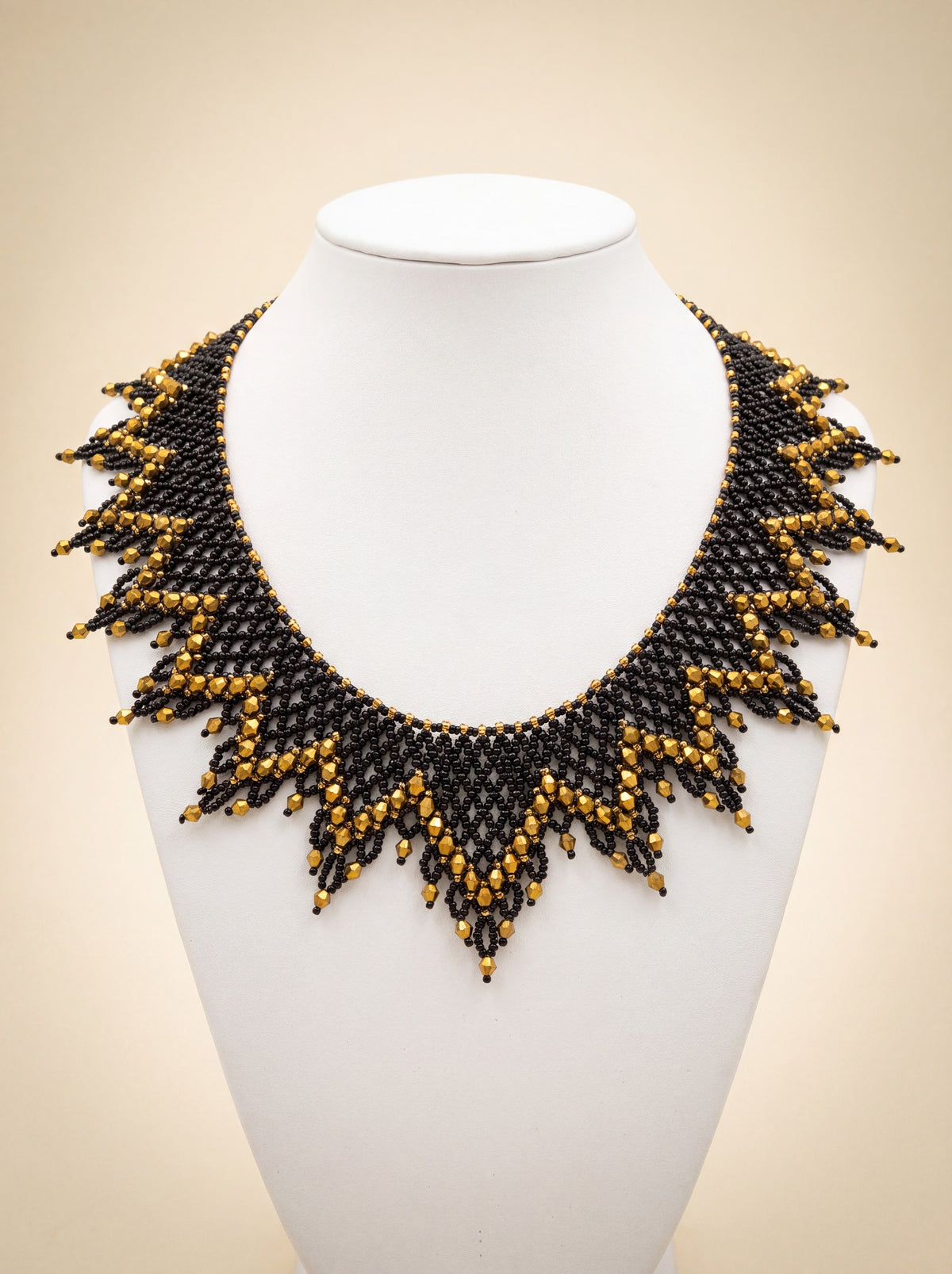 Handmade black beaded sunburst collar with a gold edge and gold crystal-tipped points, on a white bust