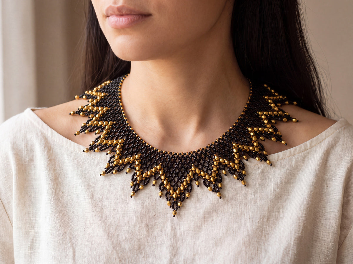 Black and gold beaded sunburst collar worn at the neckline