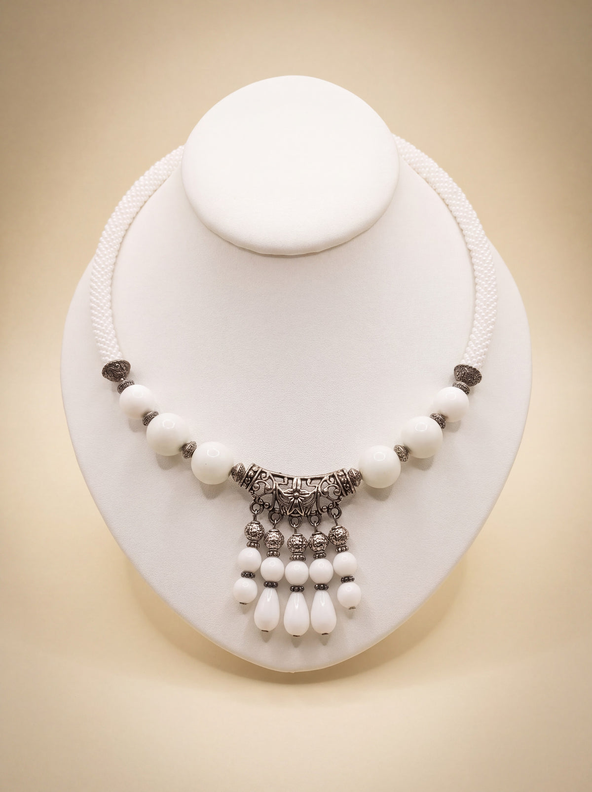 Handmade beaded rope necklace "White Queen" with white beads and an ornate silver-tone filigree pendant with dangles.