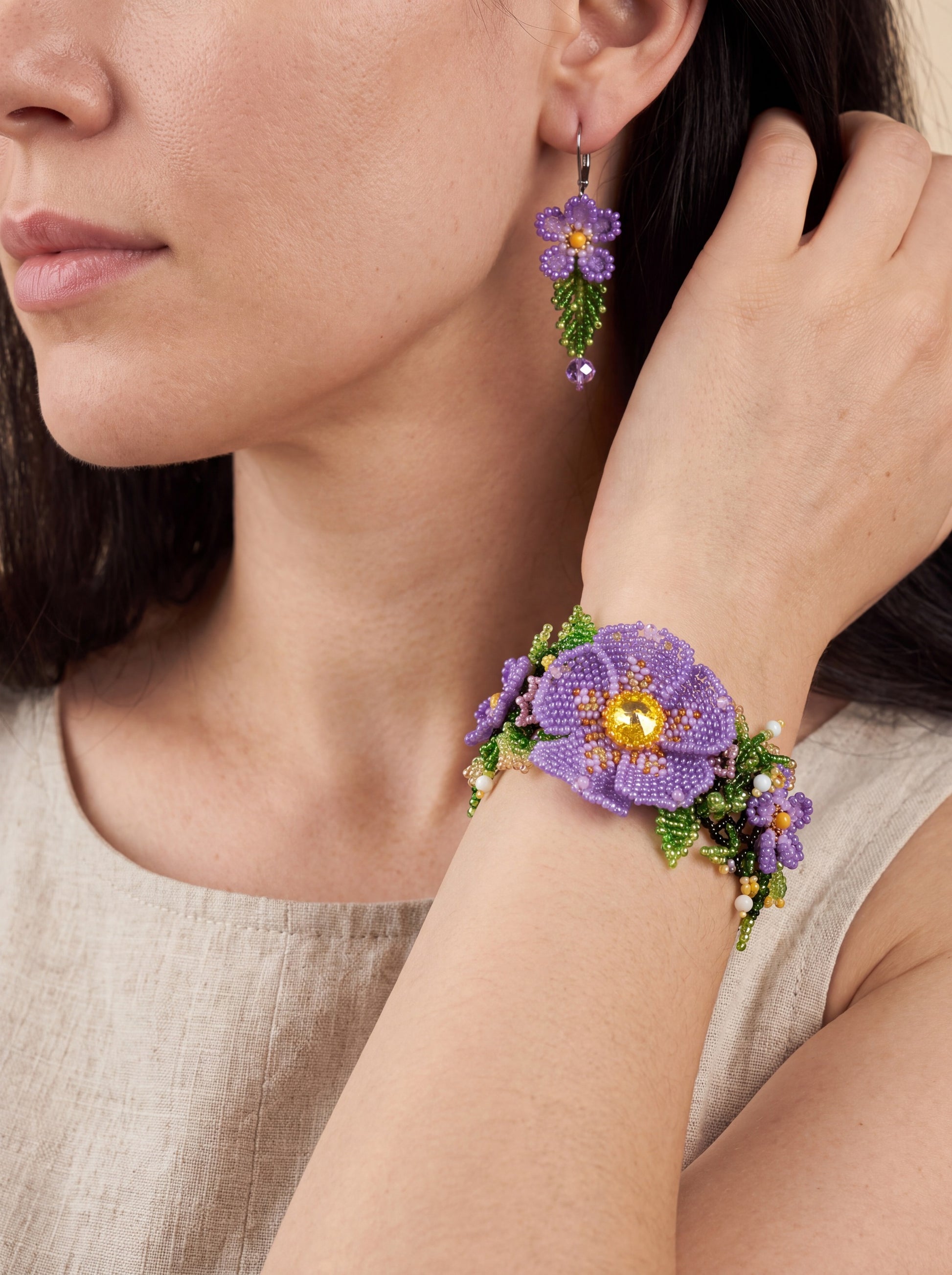 Beaded violet bracelet and earring from the "Violets" set worn together, bracelet on the wrist beside the earring