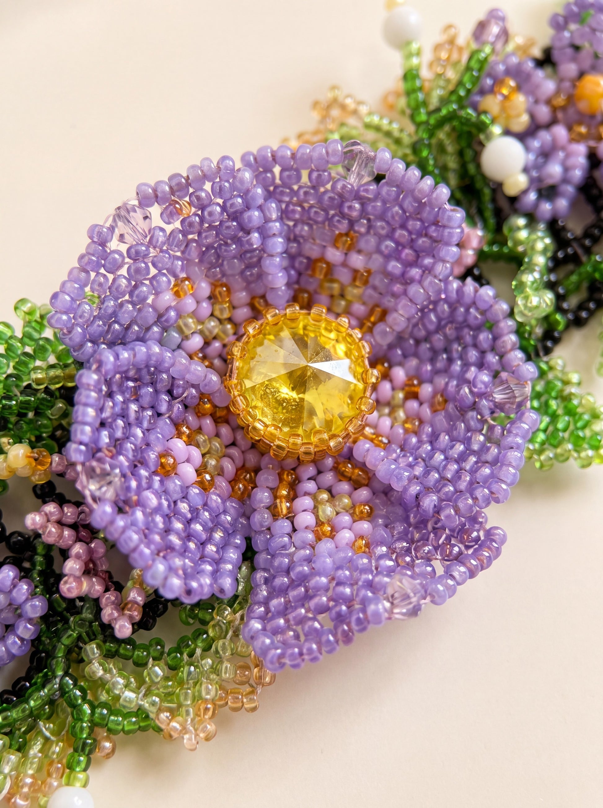 Close-up of the large purple seed-bead violet with a faceted yellow crystal centre on the "Violets" bracelet