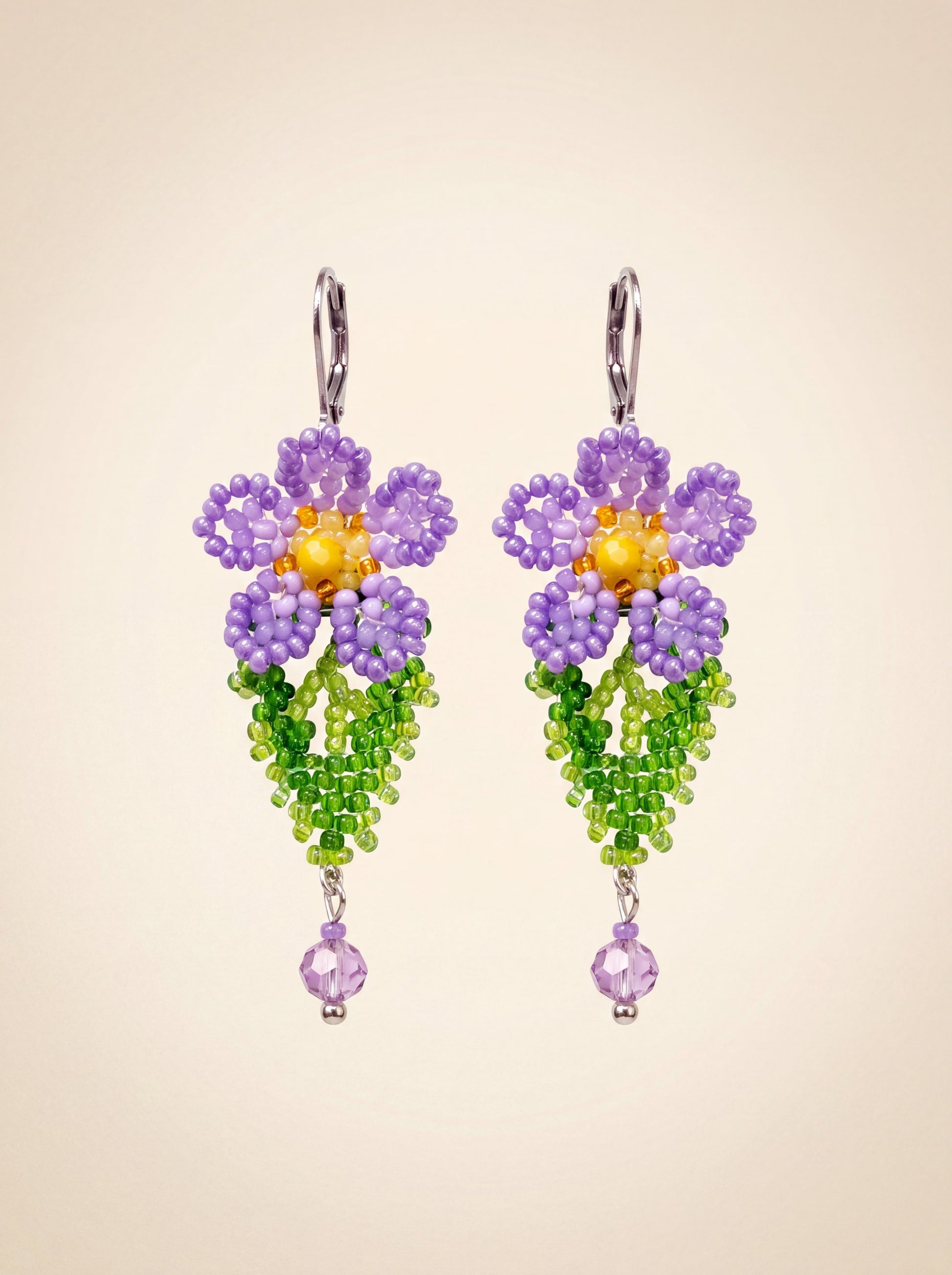 Pair of handmade beaded violet drop earrings — purple flower, green beaded leaf and lilac crystal drop on lever-back hooks