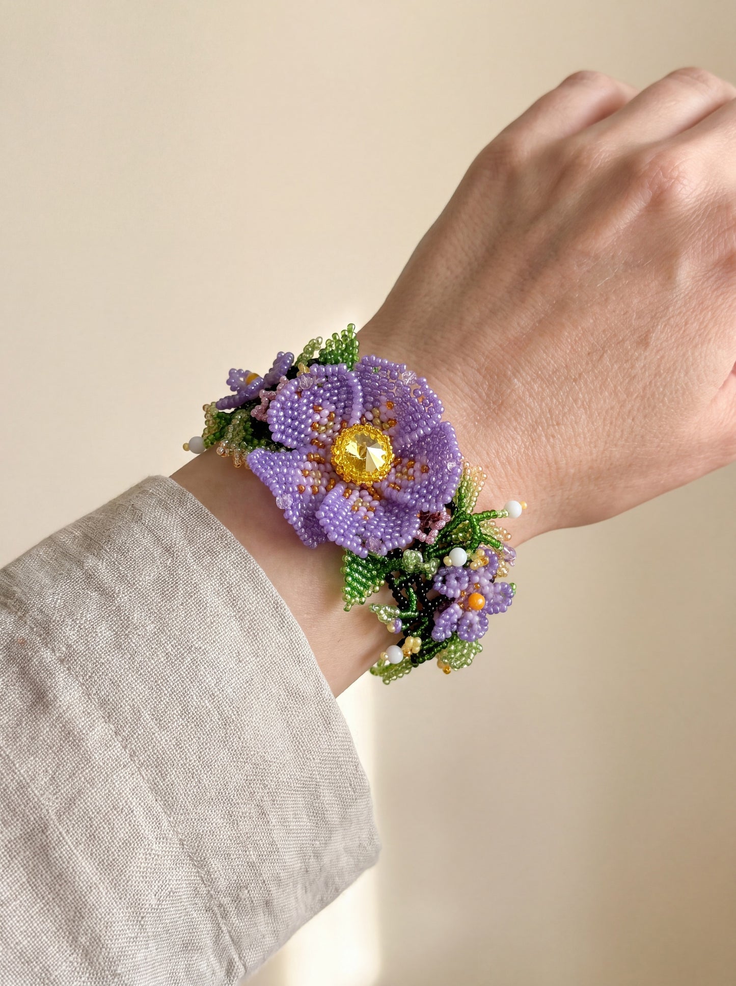 Handmade beaded violet bracelet worn on the wrist with a linen sleeve