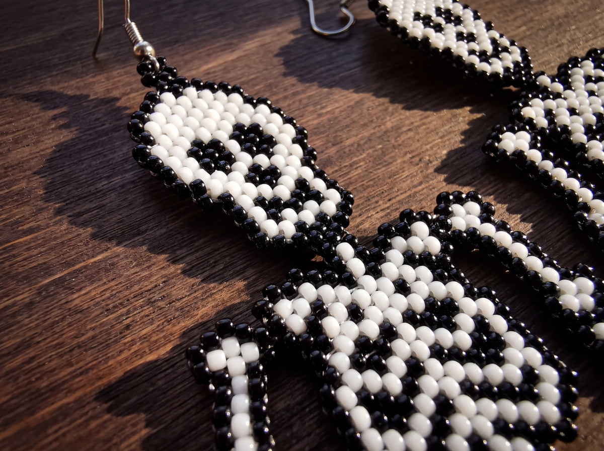 Macro detail of the beaded skull and ribcage of the skeleton earring on dark wood