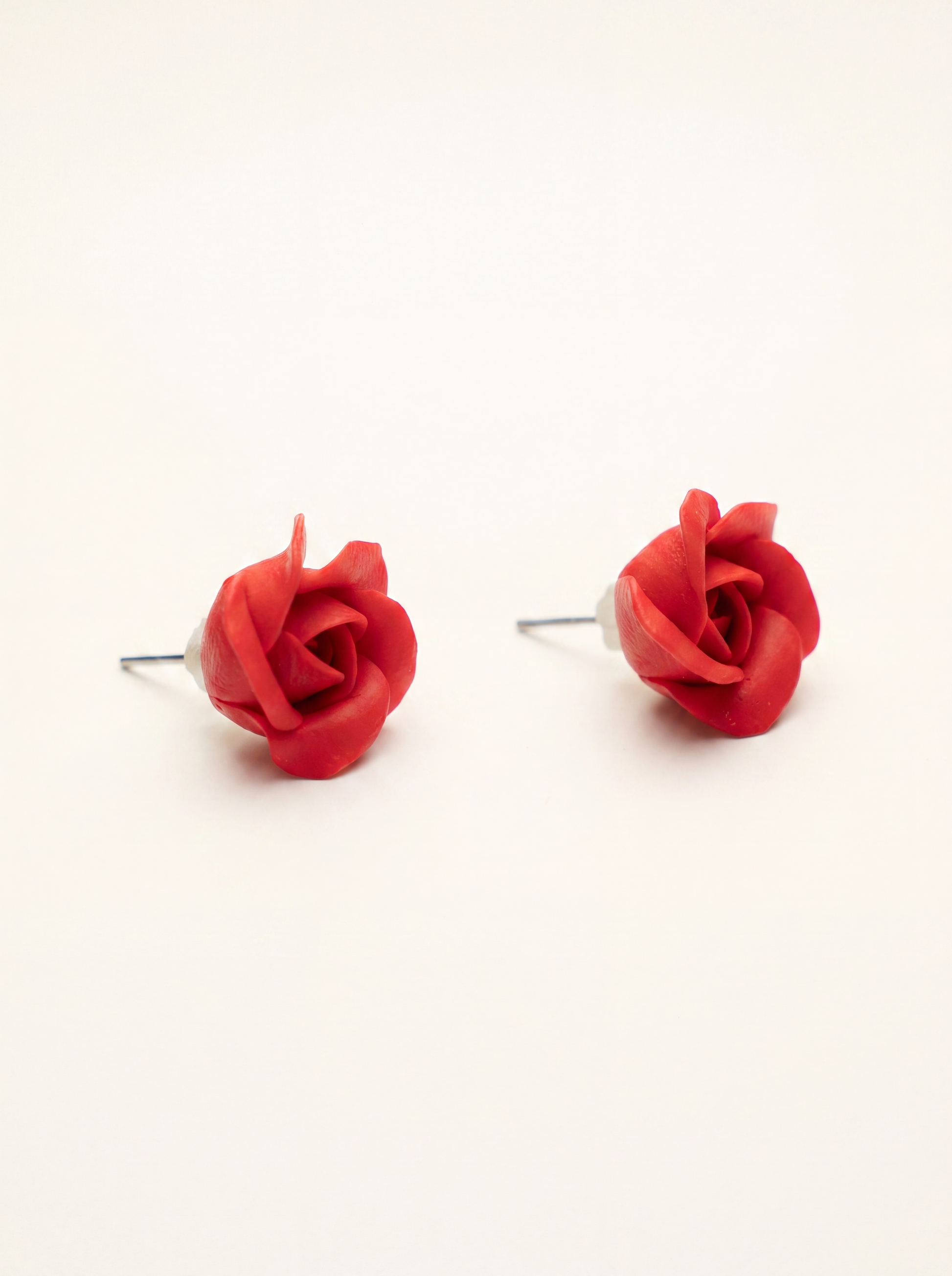 Small red rose stud earrings handmade from polymer clay with sculpted petals