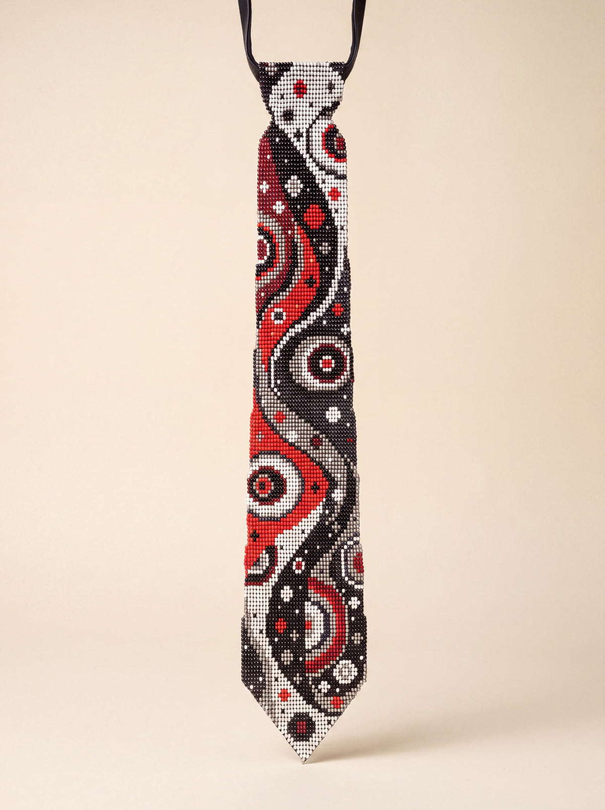 Handmade beaded necktie with a swirling red, black, white and gray abstract space-inspired pattern.